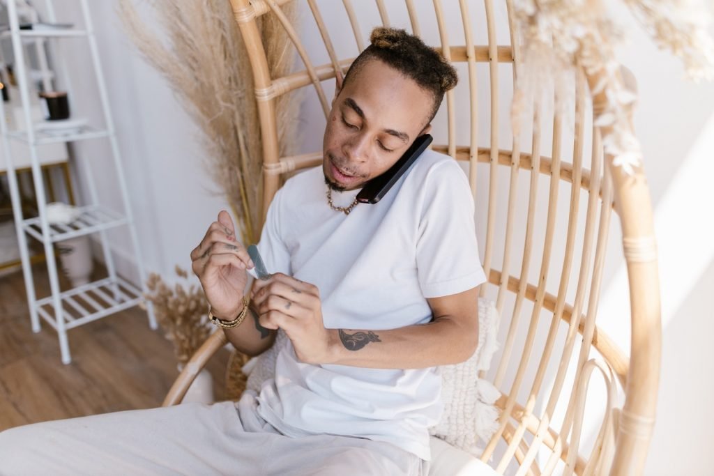 Man Sitting on a Basket Chair and Polishing His Nails
