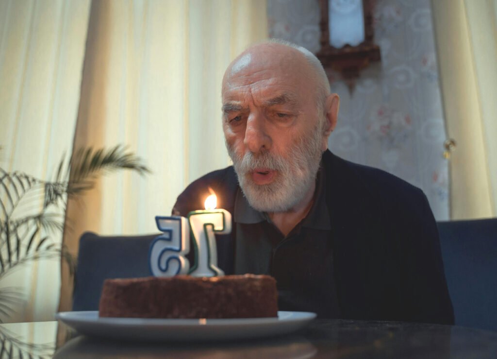 old man blowing out 75 candle